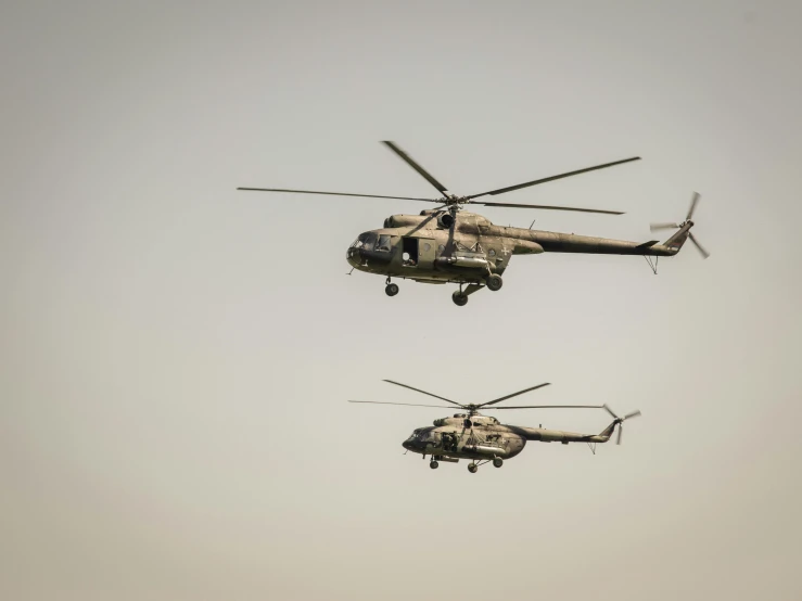 two military helicopters fly in a formation