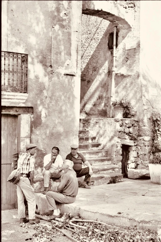 some people sitting outside on the steps near some buildings