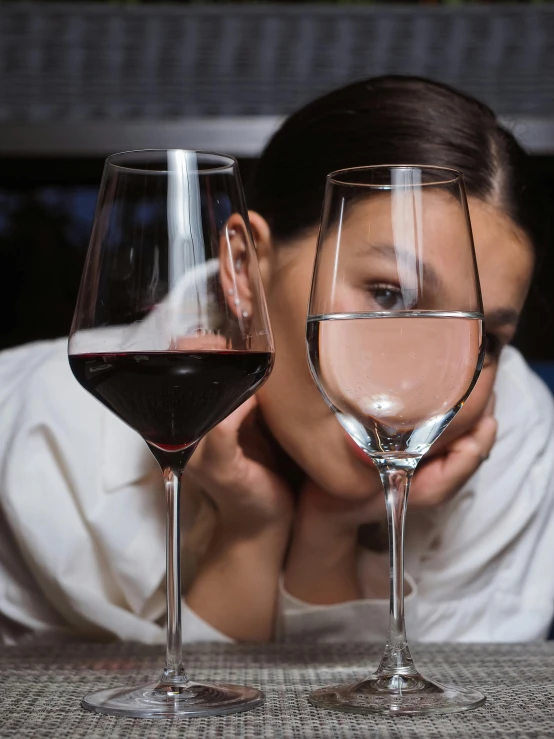 woman looking sad at two wine glasses on the table