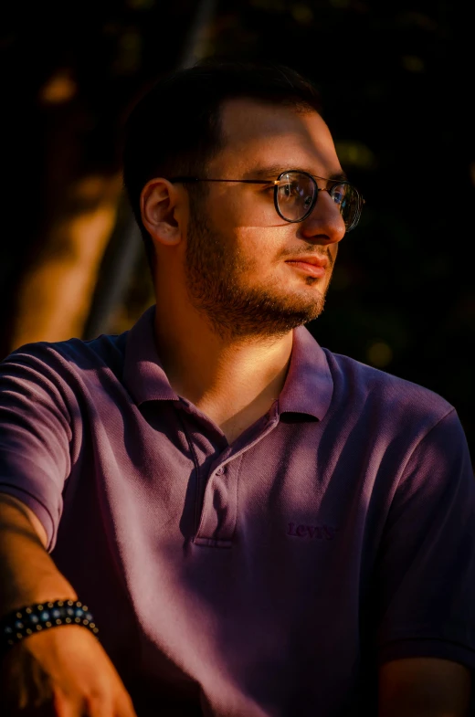 a man with glasses sitting down and staring to soing