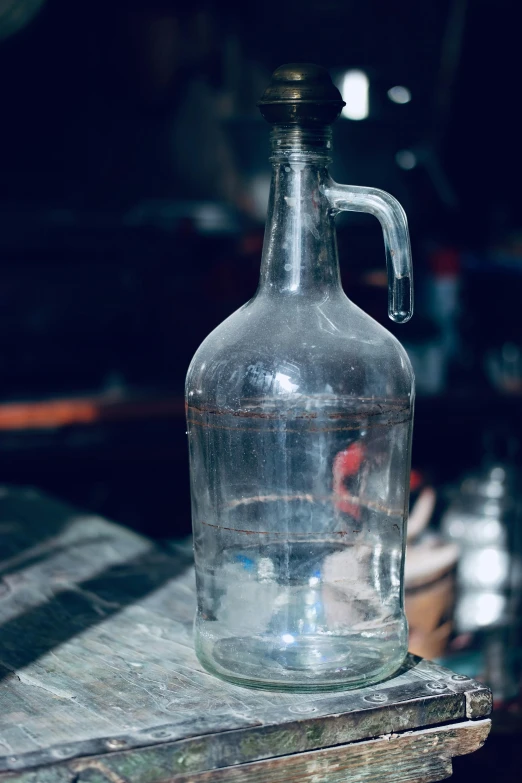 the glass jug is on the table next to some bottles