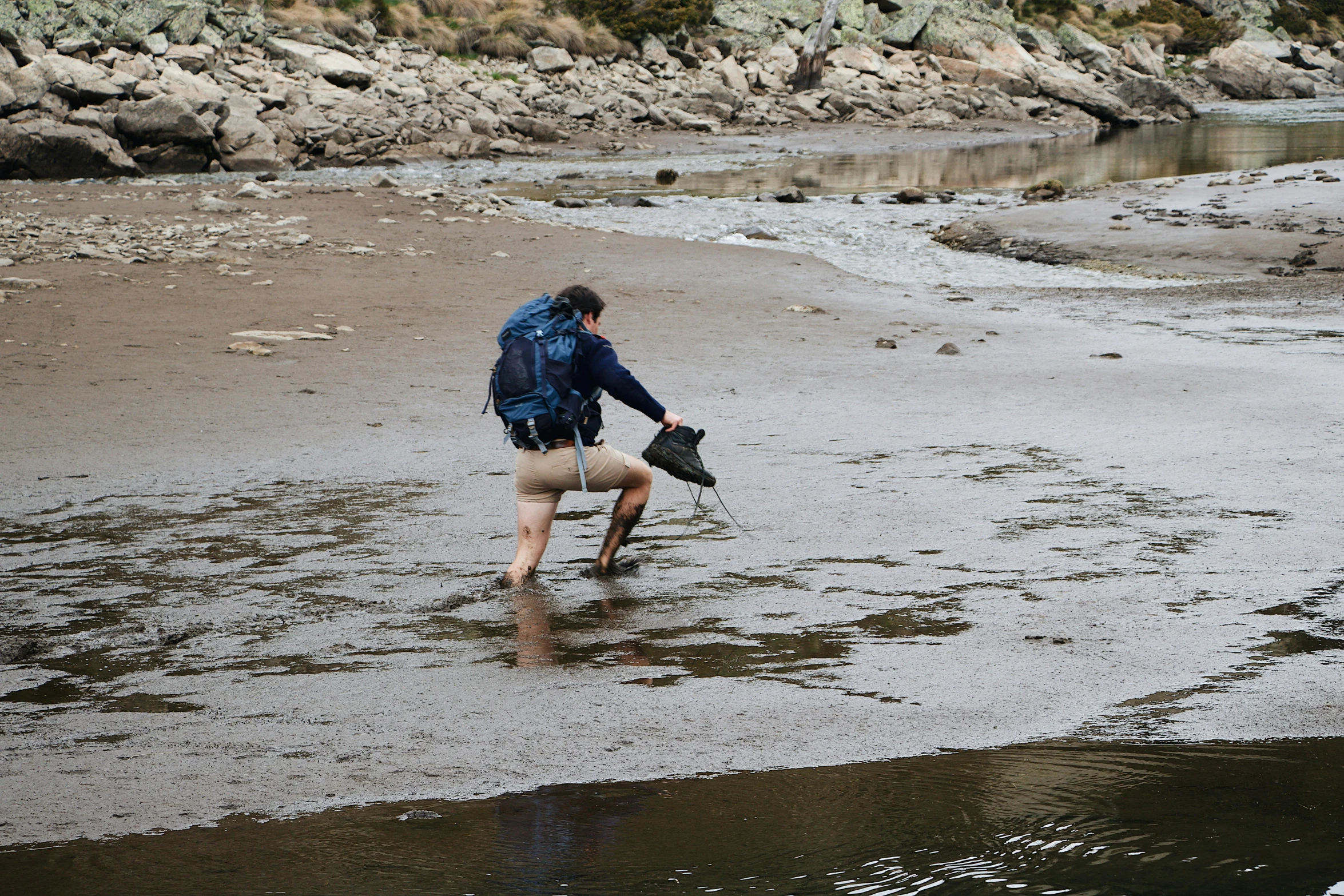 a man walking down the beach next to a body of water