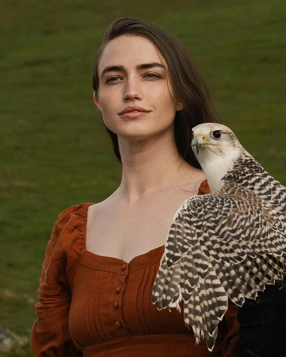 a woman holding a large bird of prey in her right hand