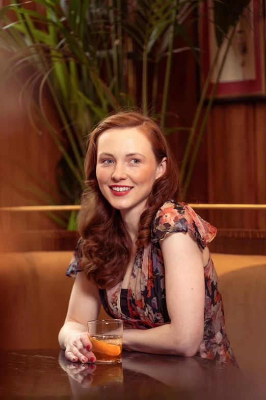 a woman sitting at a table with a drink