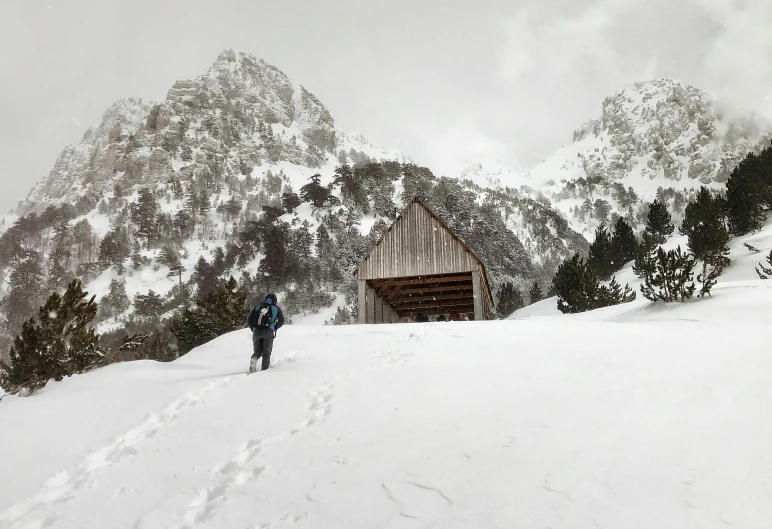 skier with backpack trekking toward a snowy cabin