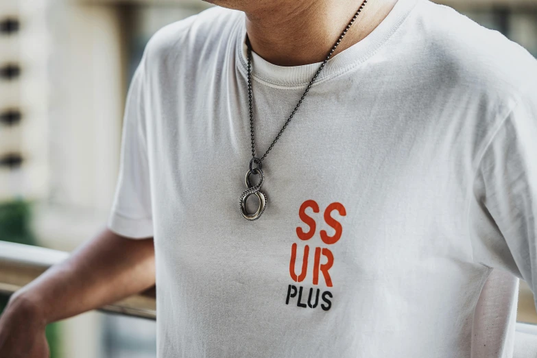 a man wearing a white shirt has a silver necklace that says ssur plus