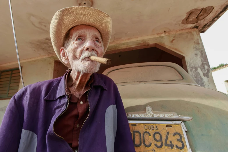 an old man with a hat, jacket and cigar