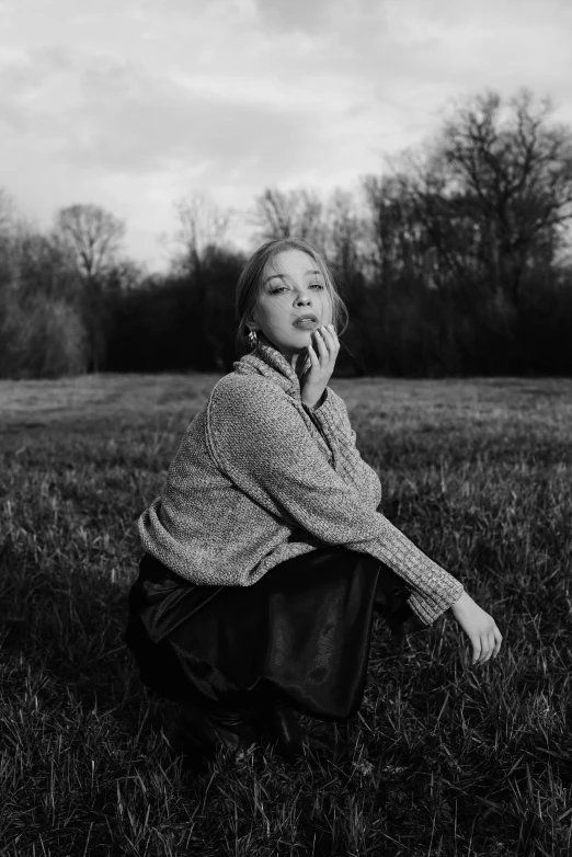 a woman sits on the grass in an open field