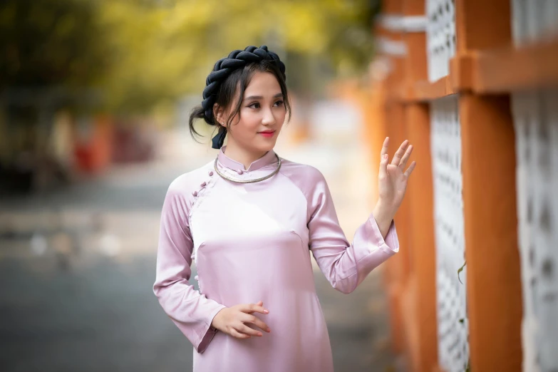 an asian woman in pink is posing by a wall