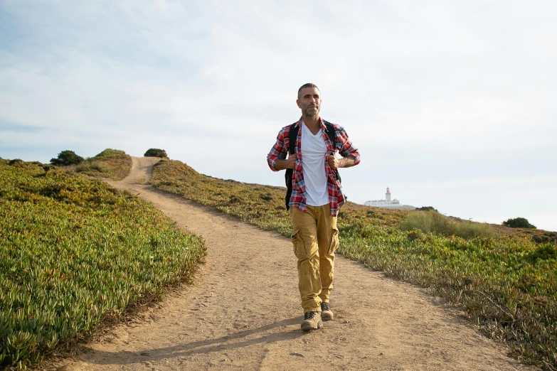 the man is standing on a dirt path looking up to his head