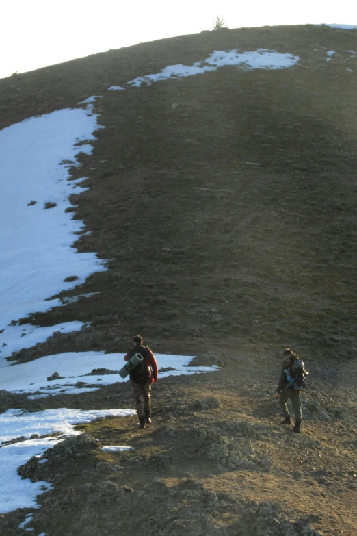 two men are hiking up a hill