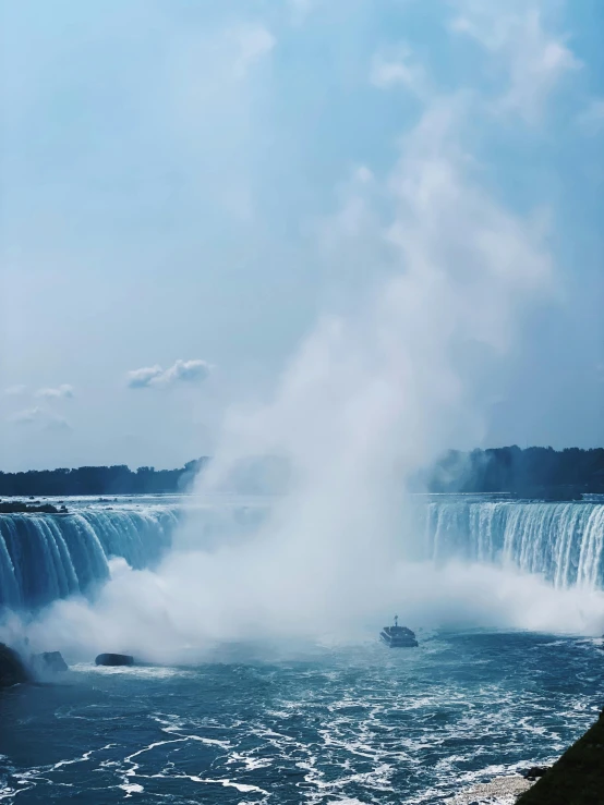 a boat sailing in the water near a waterfall