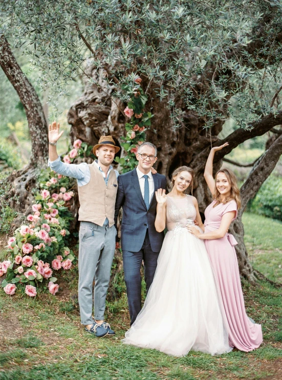 people standing under a large tree waving