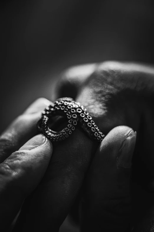 black and white pograph of two hands holding a ring