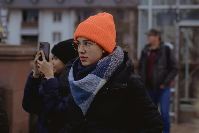 woman taking a po of another woman wearing a orange beanie
