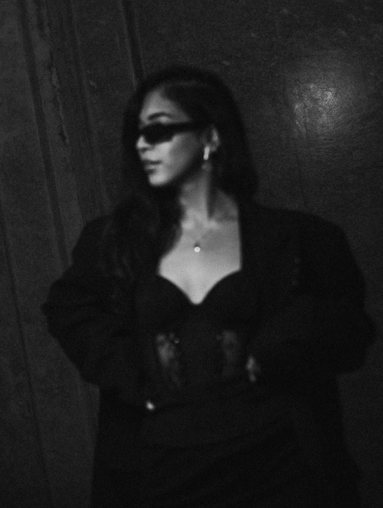 a woman standing in a dark room wearing eyeglasses