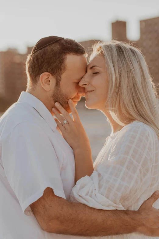 a man and woman hugging while they are standing by the ocean