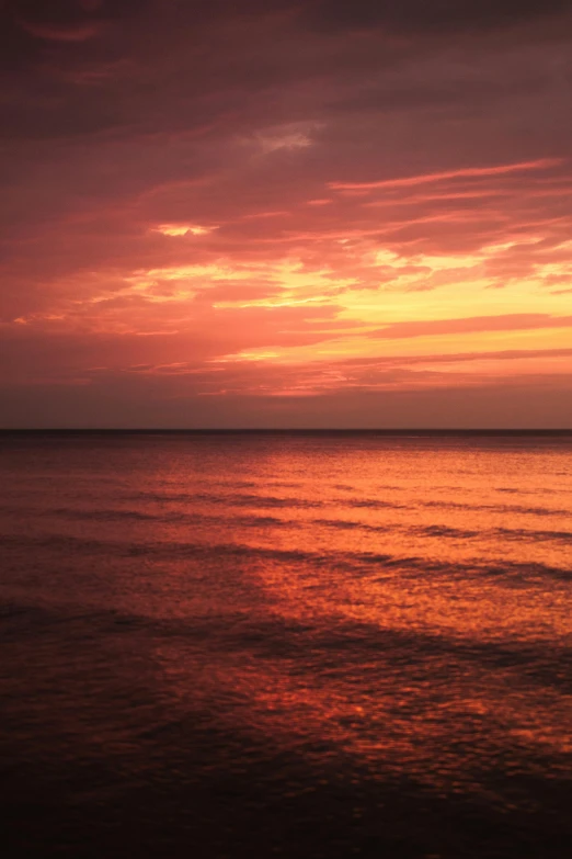 an orange sunset over the ocean with clouds