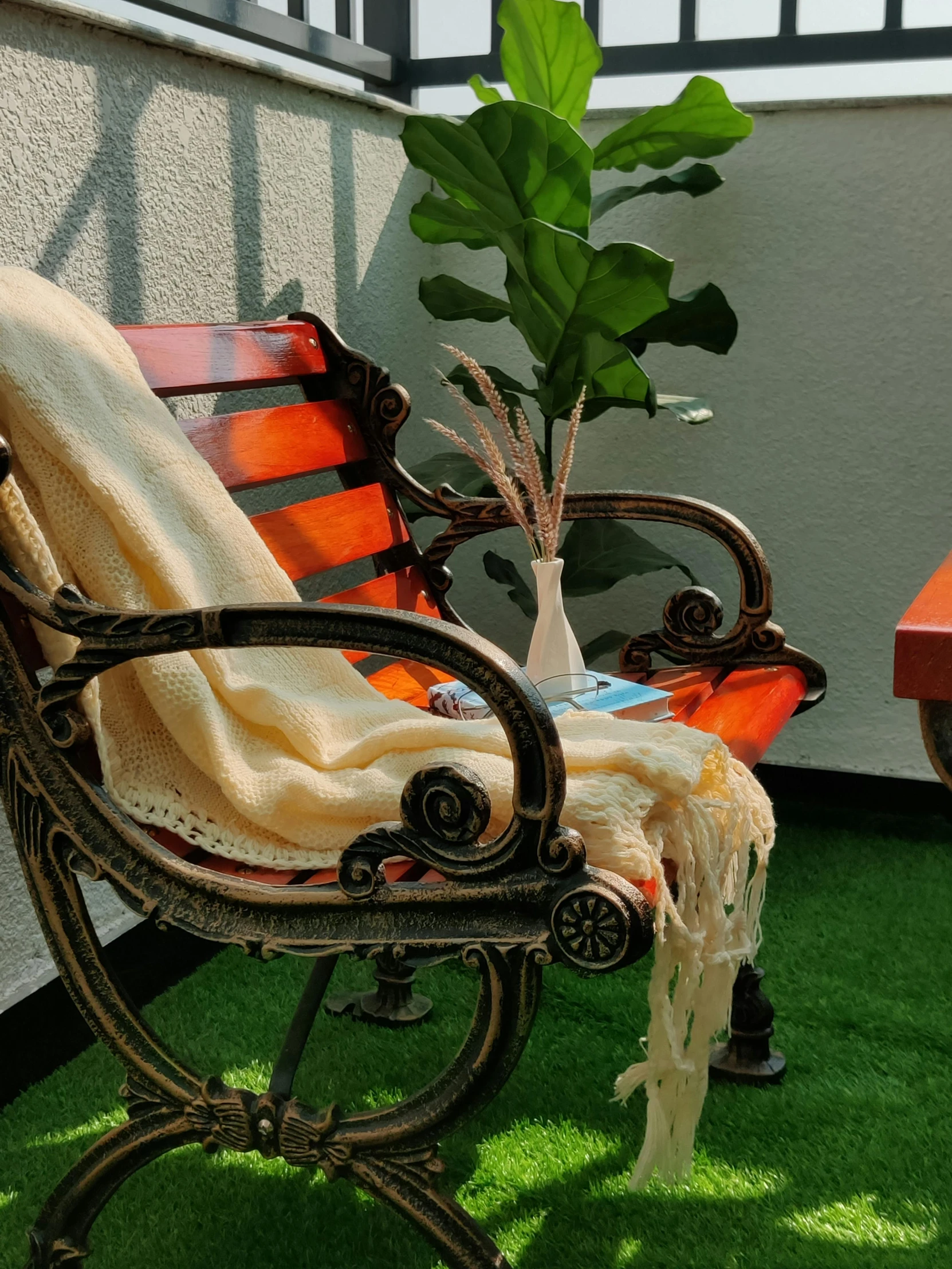 a red park bench sits next to a potted plant