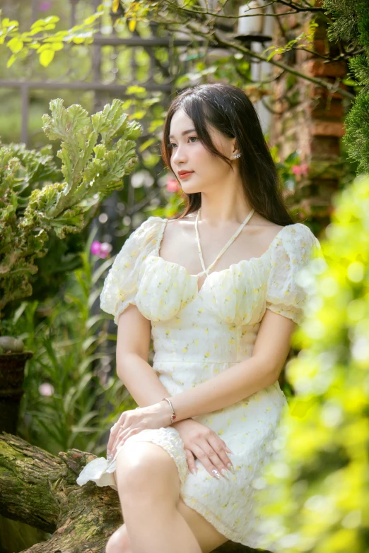 a beautiful young woman sitting in front of a green plant