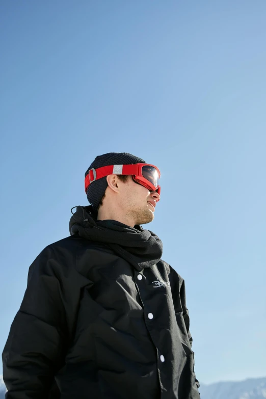 a man is standing with red ski goggles on