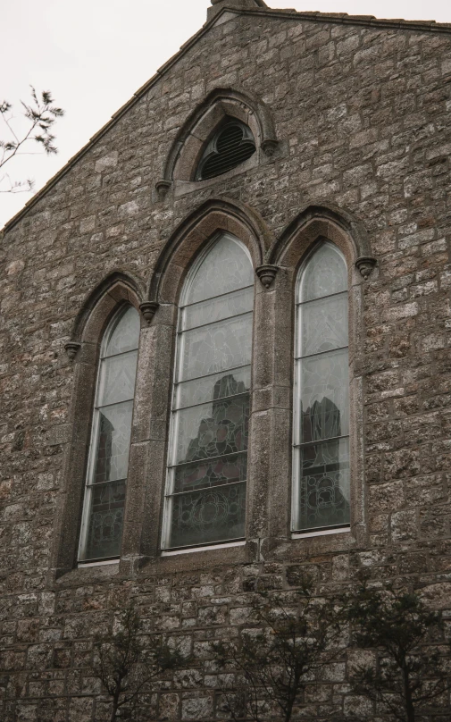 a stone building with windows and several birds flying