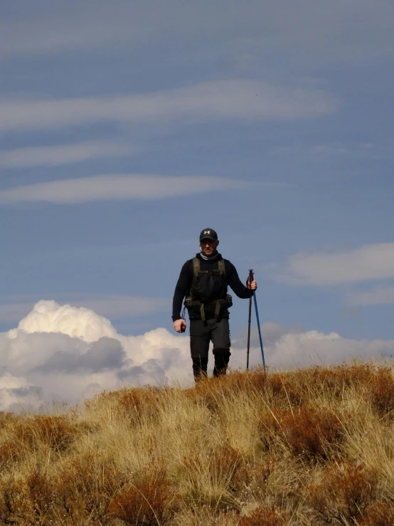 a man on top of a hill, holding some skis