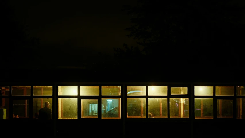 two people walking outside in front of windows at night