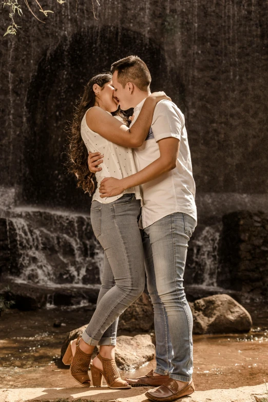 a couple kissing next to a waterfall on a beach