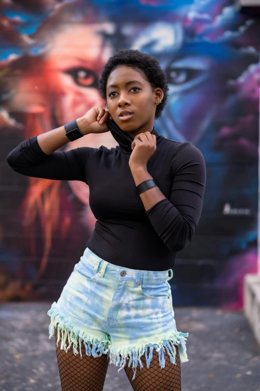 a woman in shorts standing outside next to a graffiti wall