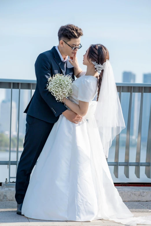 a bride and groom are standing together in front of a railing