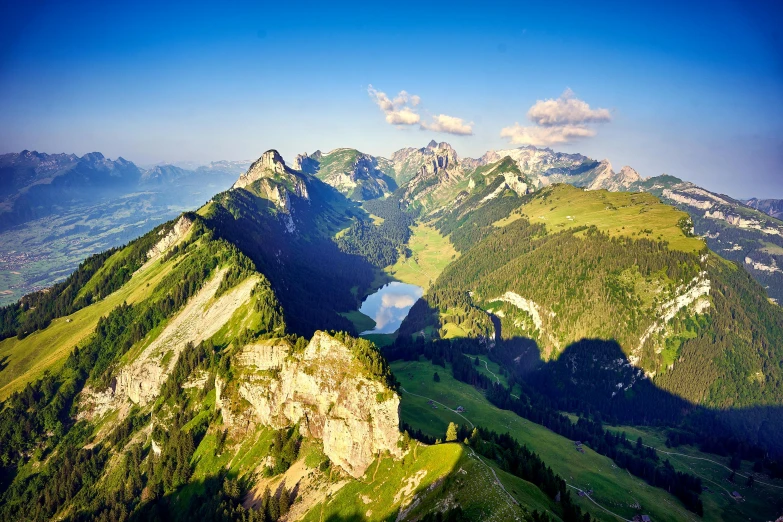 a green mountain range with a lake in the middle
