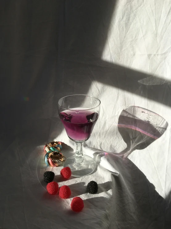 pink liquid and raspberries with some candies are on a glass