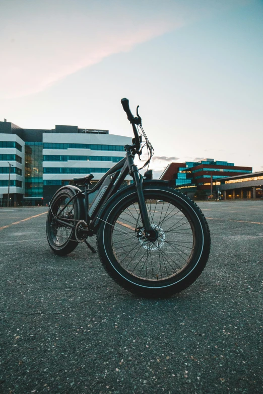 a bicycle sitting in an empty parking lot near buildings