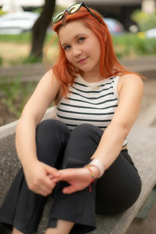 a young woman with red hair and glasses on top of a bench