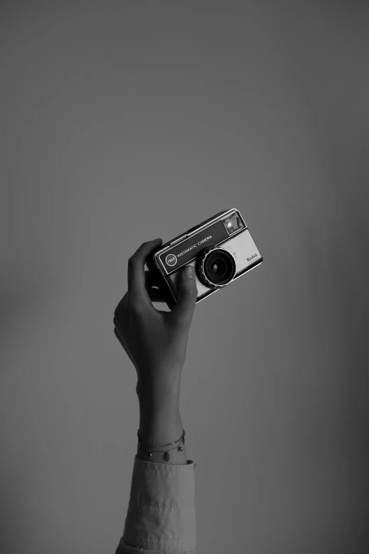 a person holding up a small camera in the air
