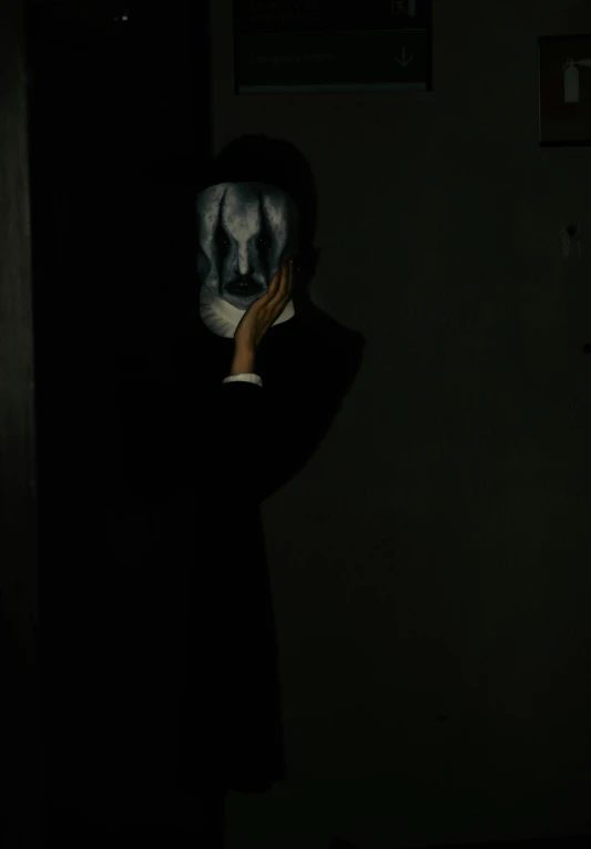 a person in a dark room covering their face with their hand