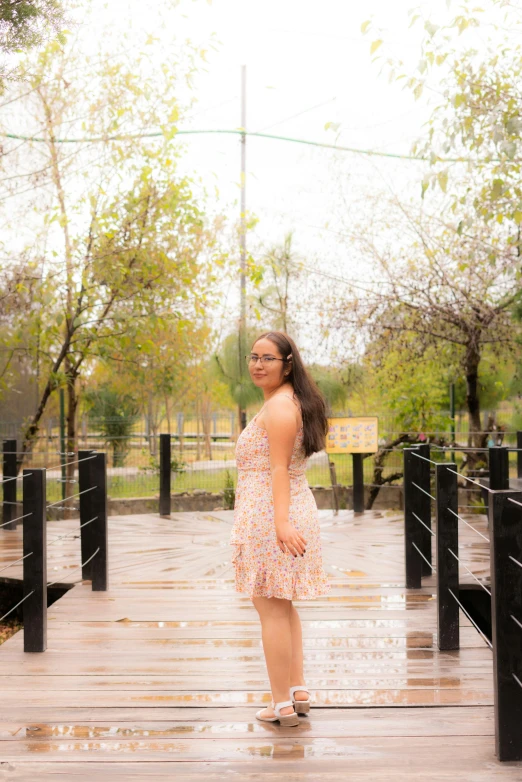 woman in pink dress posing on boardwalk in outdoor area