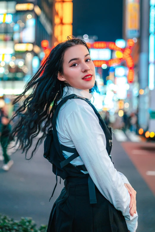 a woman wearing a back pack poses for a picture on the sidewalk