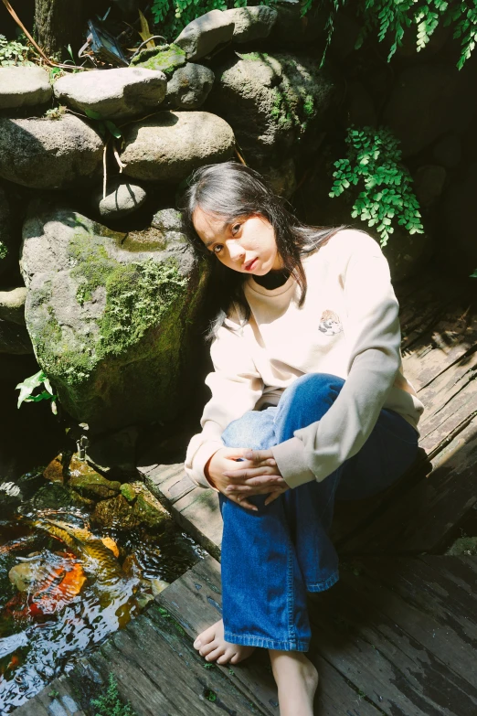 a woman sitting next to a pond with fish