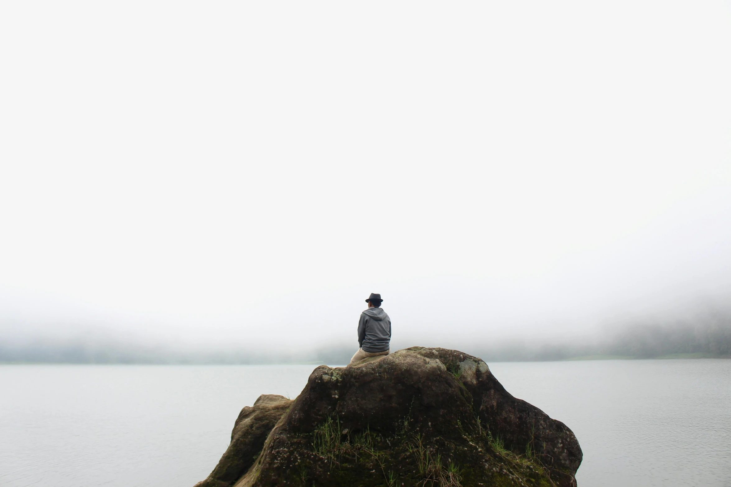 a person sits on top of a large rock