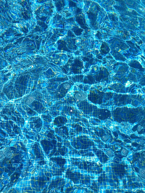 the water is reflecting sunlight and bubbles on the blue glass surface