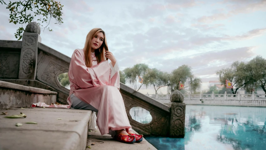a woman wearing a pink kimono sitting near a fountain