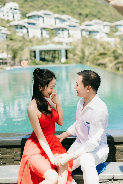 a young couple siting near the water during their engagement session