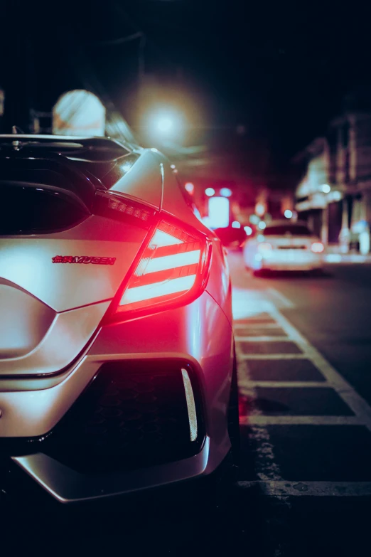 two sports cars parked in a parking lot with their headlights turned down