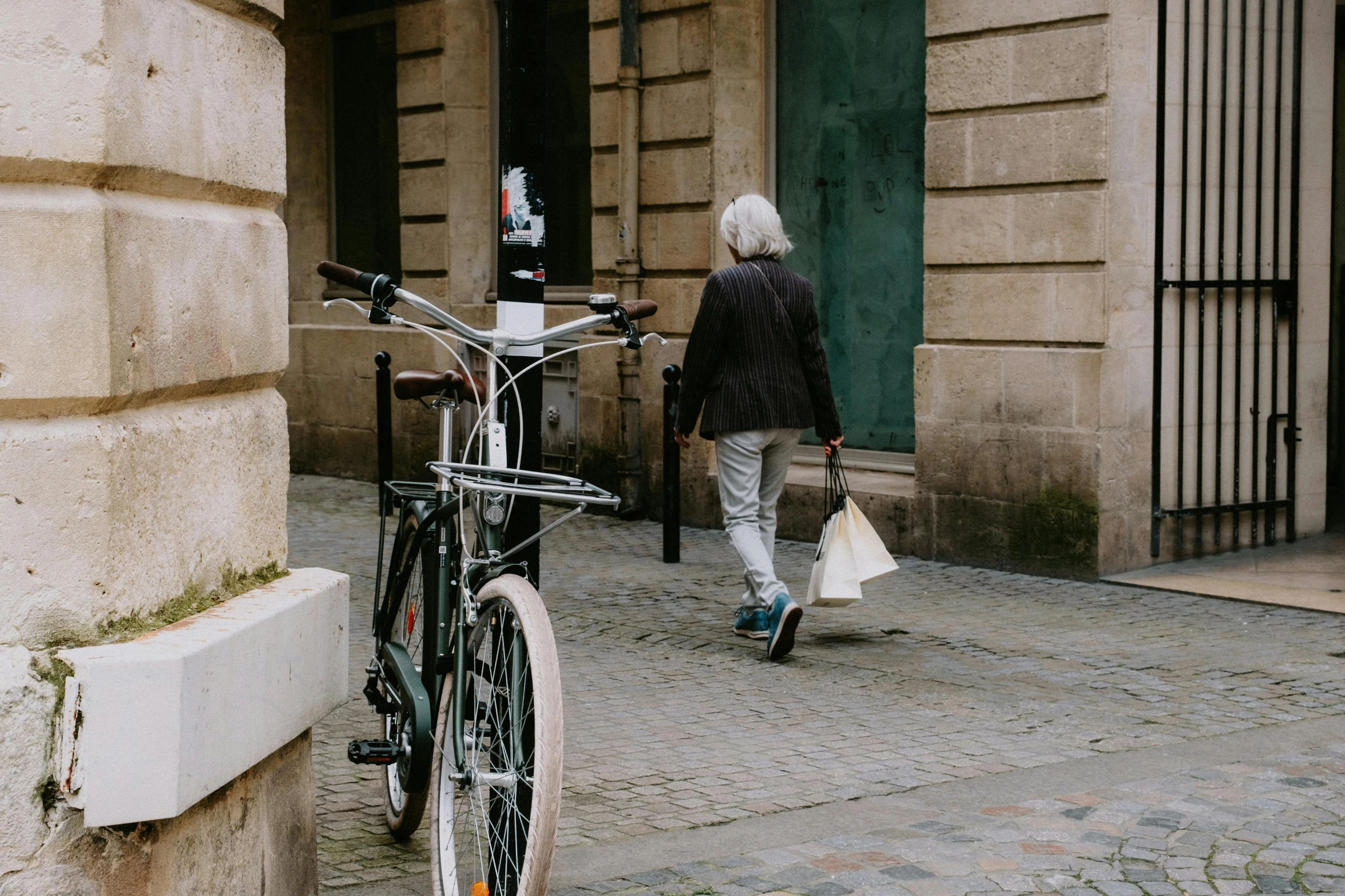 a person with white hair walking past a bicycle