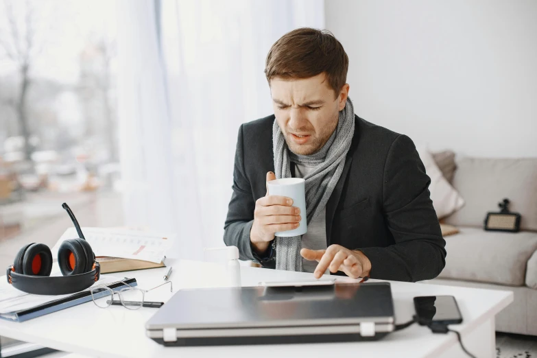 a young man is drinking a cup while doing work