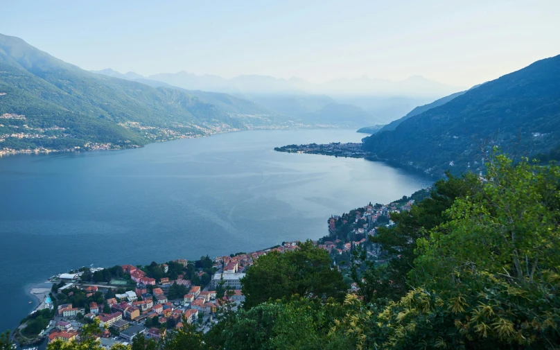 a mountain range overlooking a lake with village on the bank