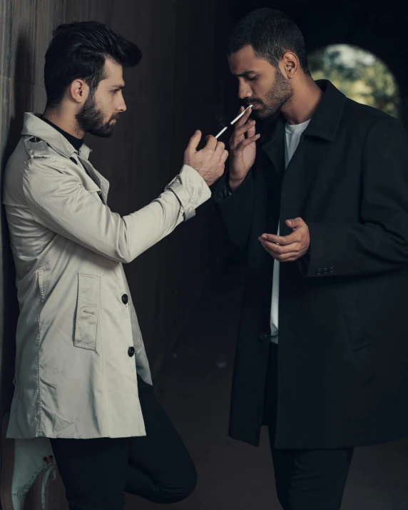 two men standing next to each other smoking