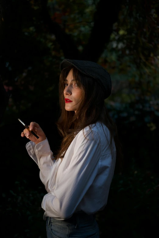 a beautiful woman in a white shirt holding onto a cigarette